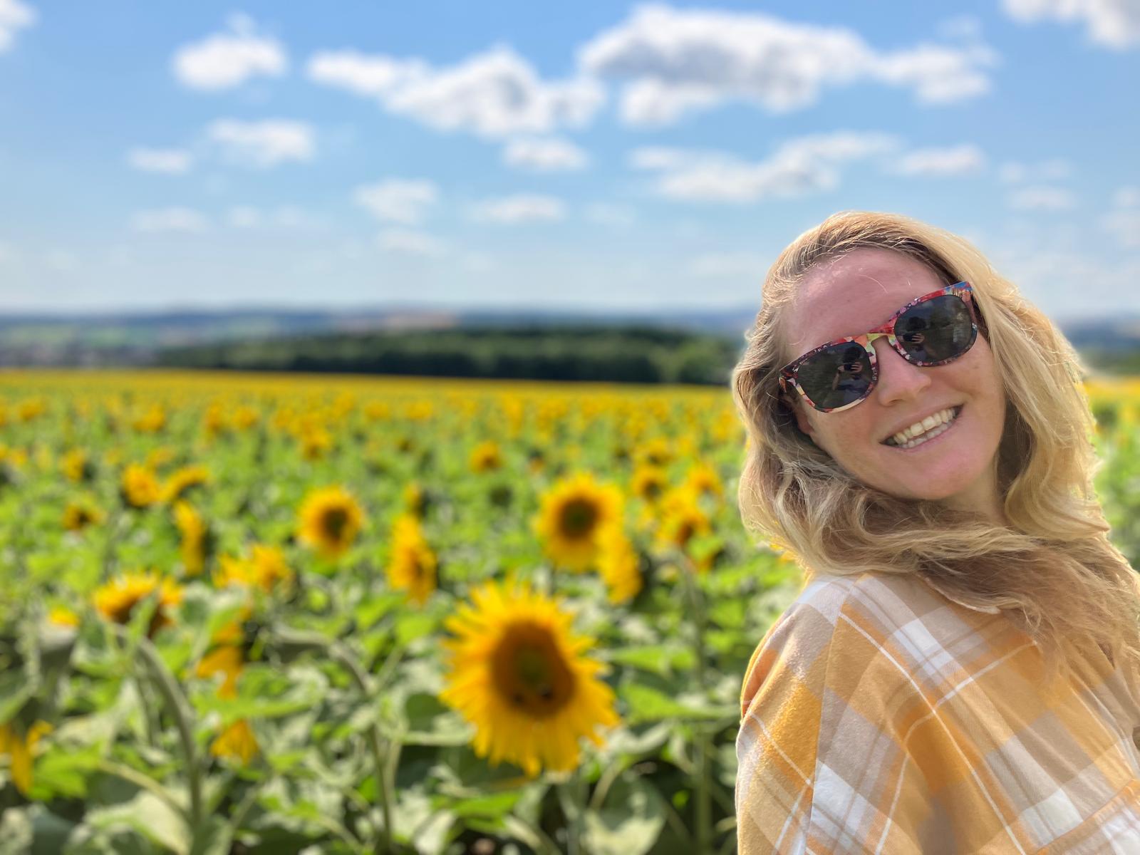 Emma Derainne standing in a sunflower field